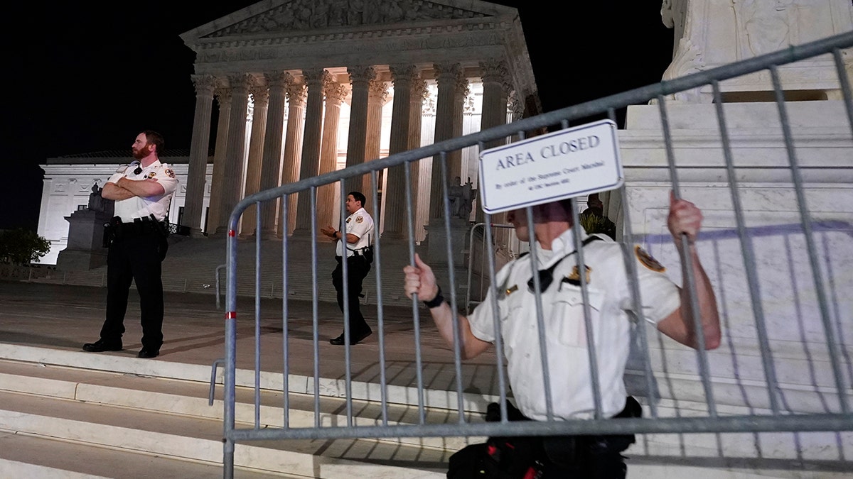 Police move barricades in place as a crowd of people gather outside the Supreme Court, Monday night, May 2, 2022 in Washington. (AP Photo/Alex Brandon)