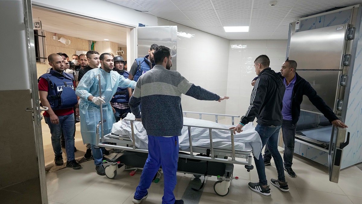 Journalists and medics wheel the body of Shireen Abu Akleh, a journalist for Al Jazeera network, into the morgue inside the Hospital in the West Bank town of Jenin, Wednesday, May 11, 2022.