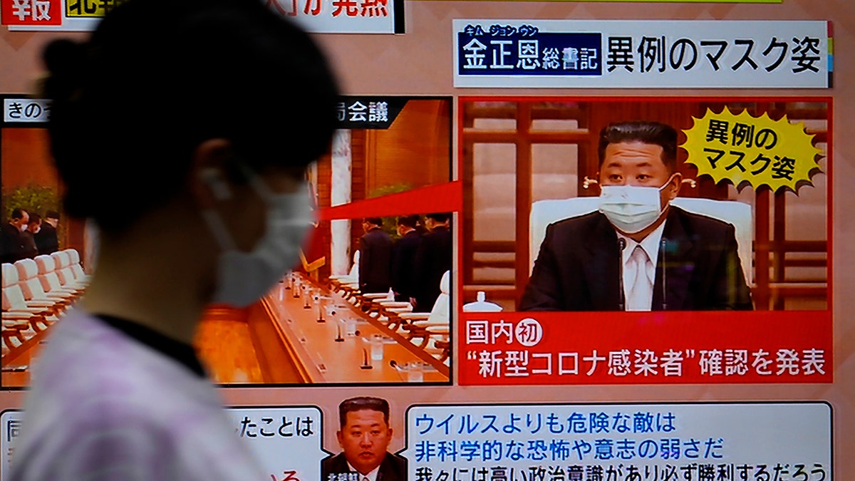 A passerby walks past a screen displaying an image of North Korean leader Kim Jong Un wearing a face mask on a TV news program in Tokyo, Friday, May 13, 2022.?