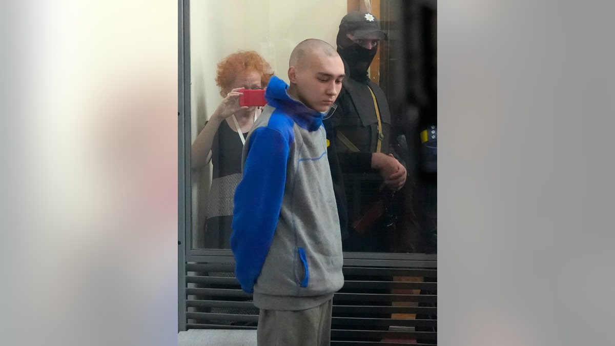 Russian army Sergeant Vadim Shishimarin, 21, is seen behind a glass during a court hearing in Kyiv, Ukraine, Friday, May 13, 2022. The trial of a Russian soldier accused of killing a Ukrainian civilian opened Friday, the first war crimes trial since Moscow's invasion of its neighbor. (AP Photo/Efrem Lukatsky)