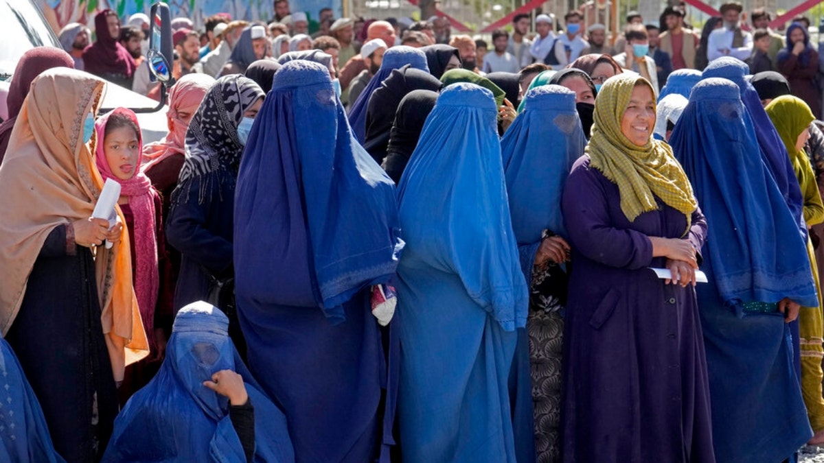 Hundreds of Afghan women in burqas wait to receive food rations