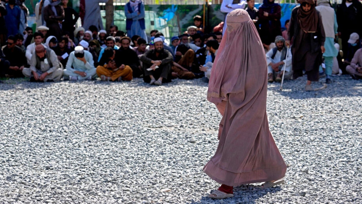 An Afghan woman waits to receives food rations