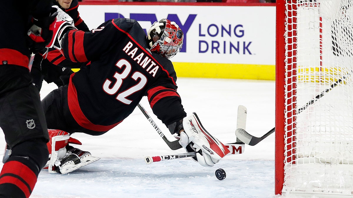 Carolina Hurricanes goaltender Antti Raanta (32) dives for the puck against the Boston Bruins during the first period of Game 1 of an NHL hockey Stanley Cup first-round playoff series in Raleigh, N.C., Monday, May 2, 2022.