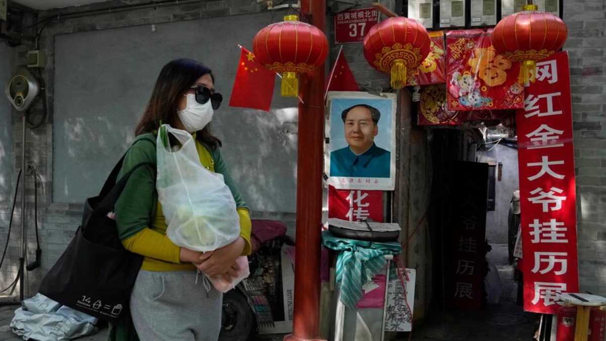 A Beijing resident walks past a home with a portrait of Chinese leader Mao Zedong