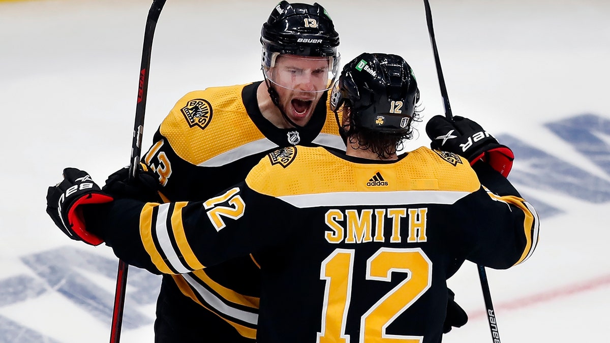 Boston Bruins' Charlie Coyle (13) celebrates his goal with Craig Smith (12) during the second period against the Carolina Hurricanes in Game 6 of an NHL hockey Stanley Cup first-round playoff series Thursday, May 12, 2022, in Boston. 