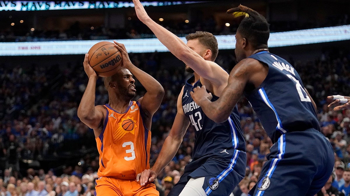 Phoenix Suns guard Chris Paul (3) works to pass the ball as Dallas Mavericks forward Maxi Kleber (42) and Reggie Bullock, right, defend in the first half of Game 4 of an NBA basketball second-round playoff series, Sunday, May 8, 2022, in Dallas. 