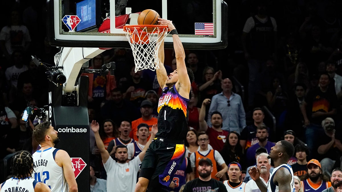 Phoenix Suns guard Devin Booker (1) dunks against Dallas Mavericks guard Jalen Brunson (13), Mavericks forwards Maxi Kleber (42) and Dorian Finney-Smith, right, during the first half of Game 5 of an NBA basketball second-round playoff series Tuesday, May 10, 2022, in Phoenix. 
