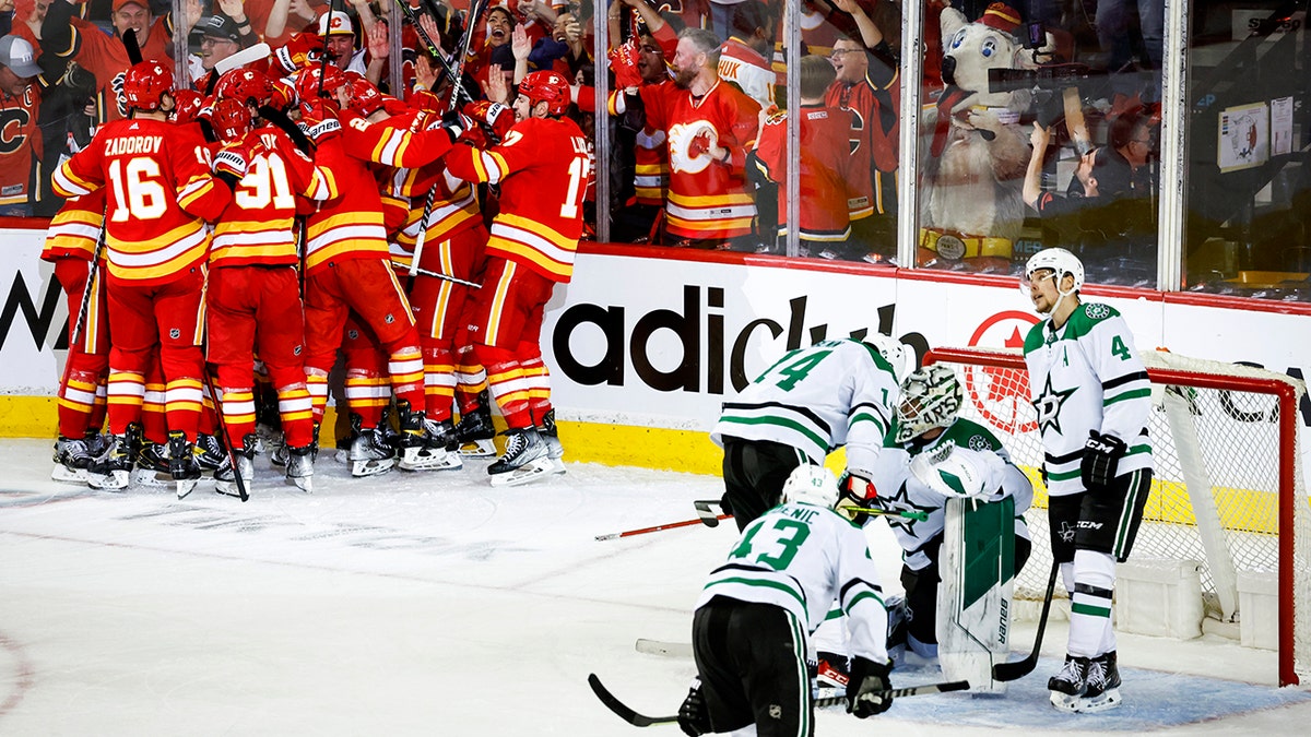 Dallas Stars goalie Jake Oettinger is consoled by teammates as Flames celebrate in Calgary, Alberta, Sunday, May 15, 2022.