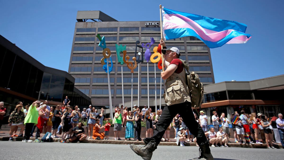 An activist hold a trans pride flag in Portland, Maine