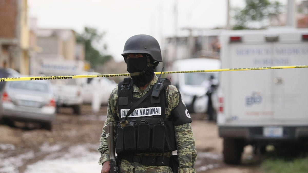Mexico national police officer stands by crime scene tape