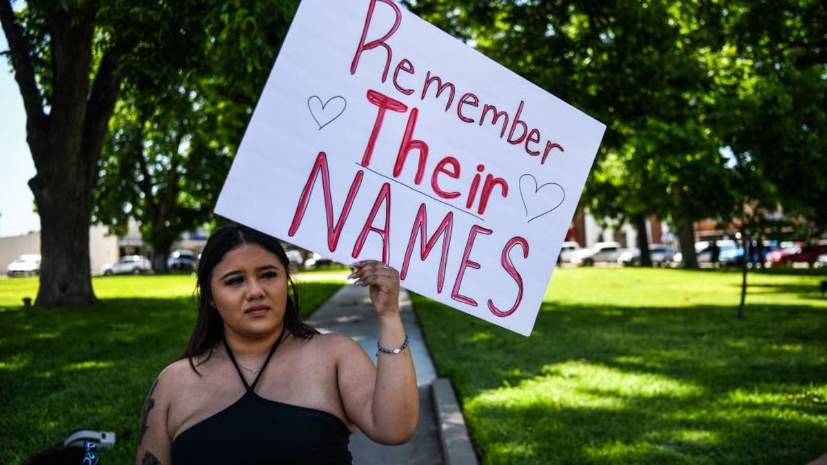 A woman holds a sign that reads, 'Prayers 4 Uvalde'