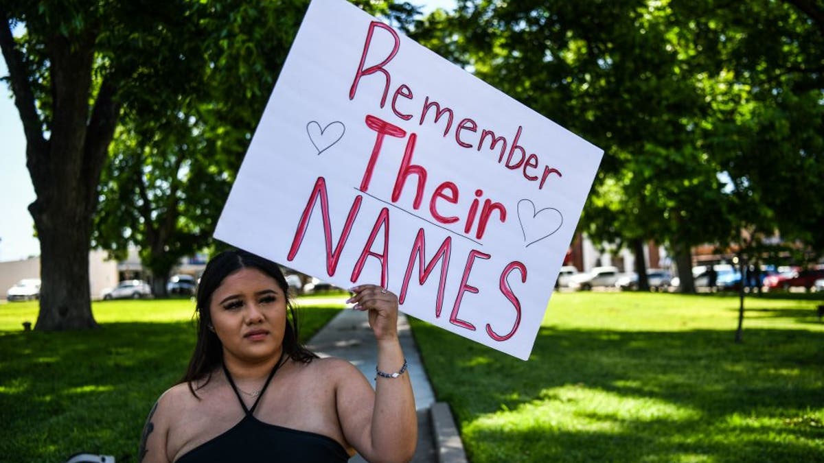 A woman holds a sign that reads, 'Prayers 4 Uvalde'