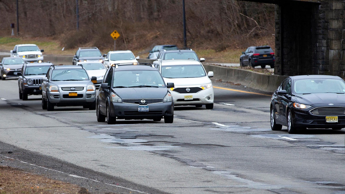 Cars drive on road with potholes