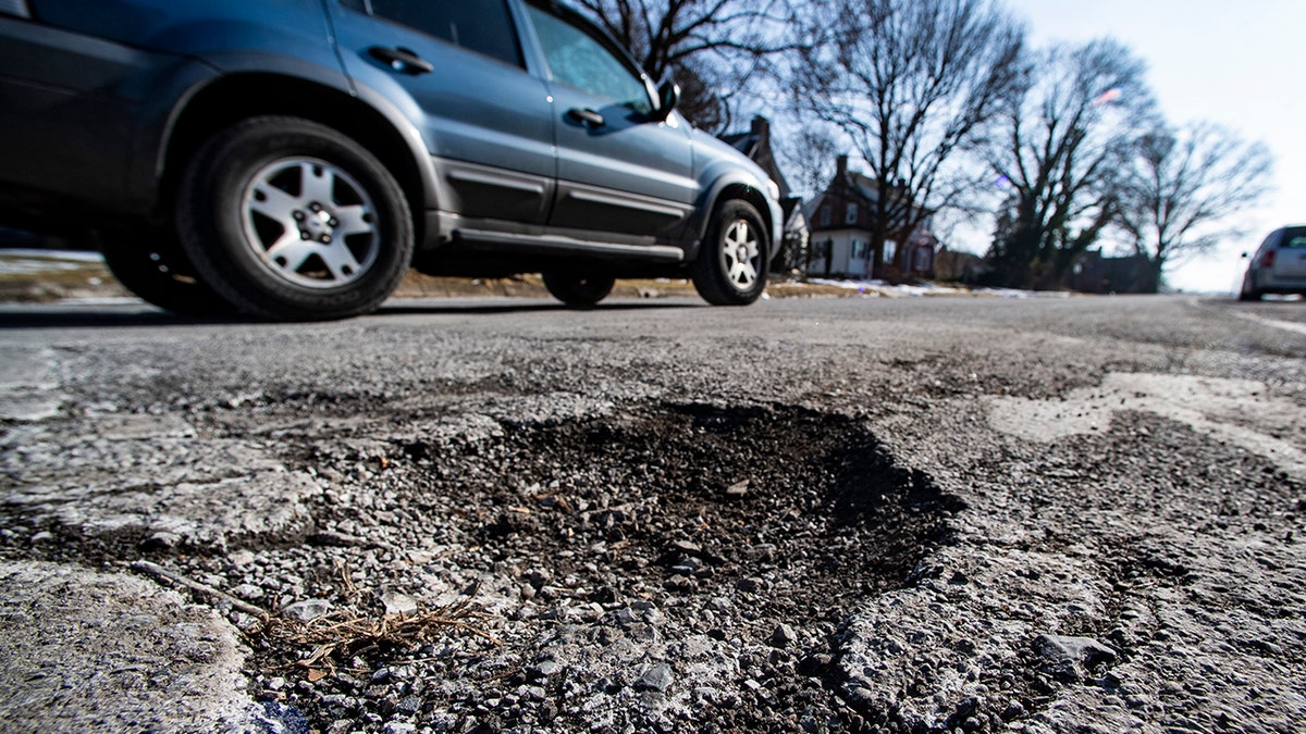 car drives past pothole