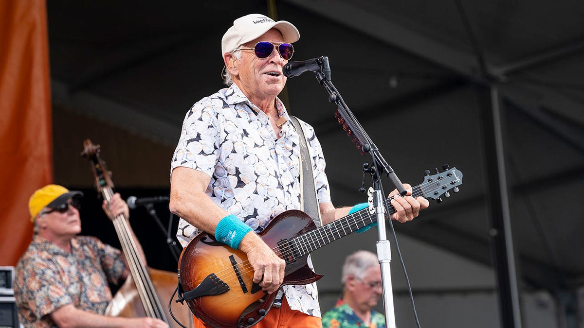 Jimmy Buffett holds guitar on stage