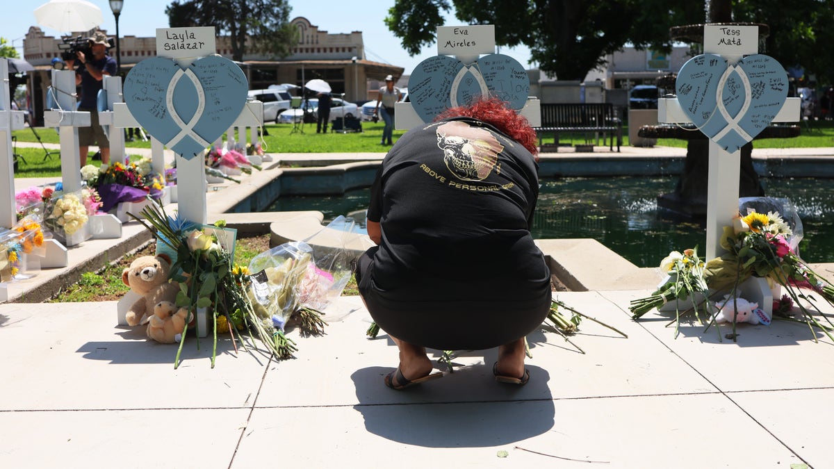 A woman kneels at a memorial for one of victims in a school shooting