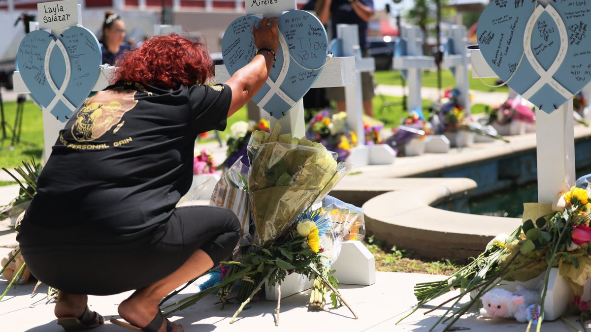 A woman places her hand on top of a memorial