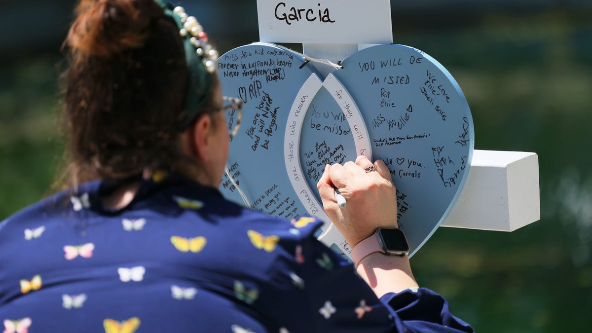 A woman writes a message on a memorial