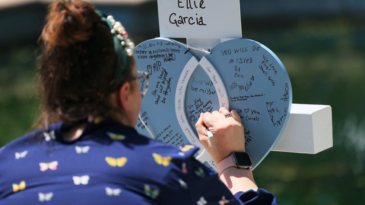 A woman writes a message on a memorial