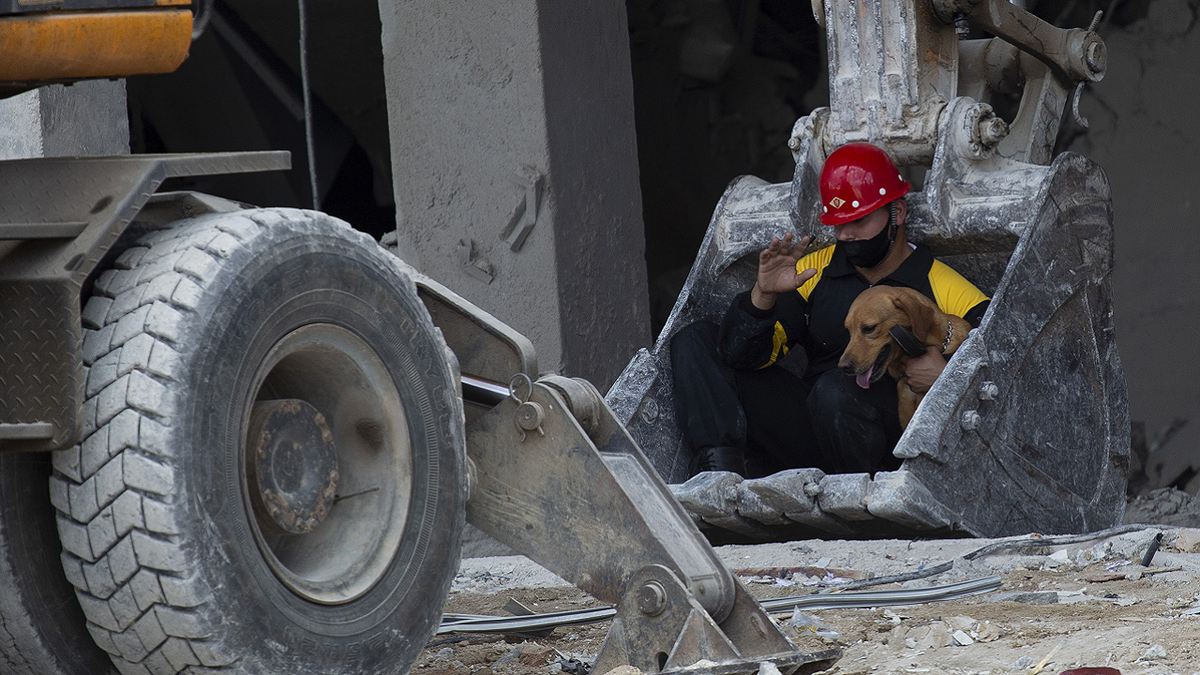 A rescue worker and his search dog are transported on the shovel of an excavator on Sunday, May 8, to search for survivors at the site of the Hotel Saratoga in Old Havana. 