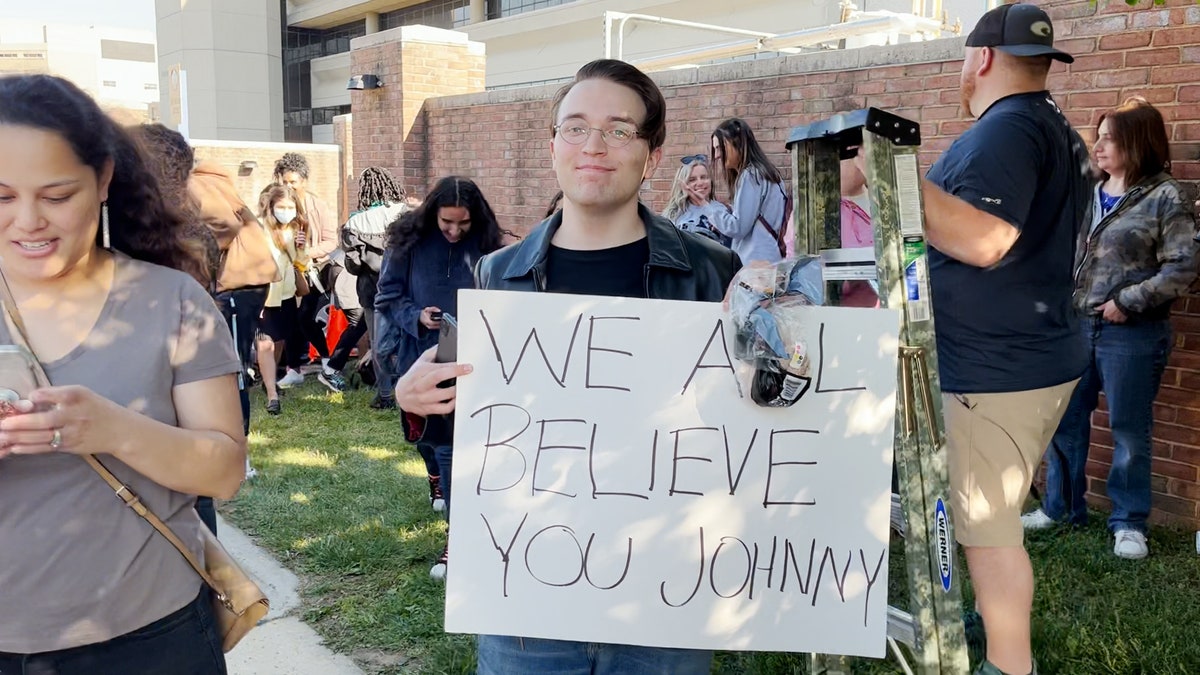 A Depp fan holds up a "We all believe you Johnny" sign