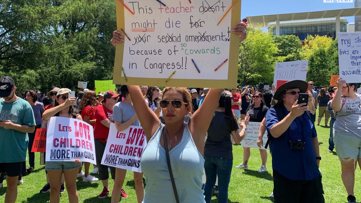 A woman holds an anti-gun sign protesting the NRA