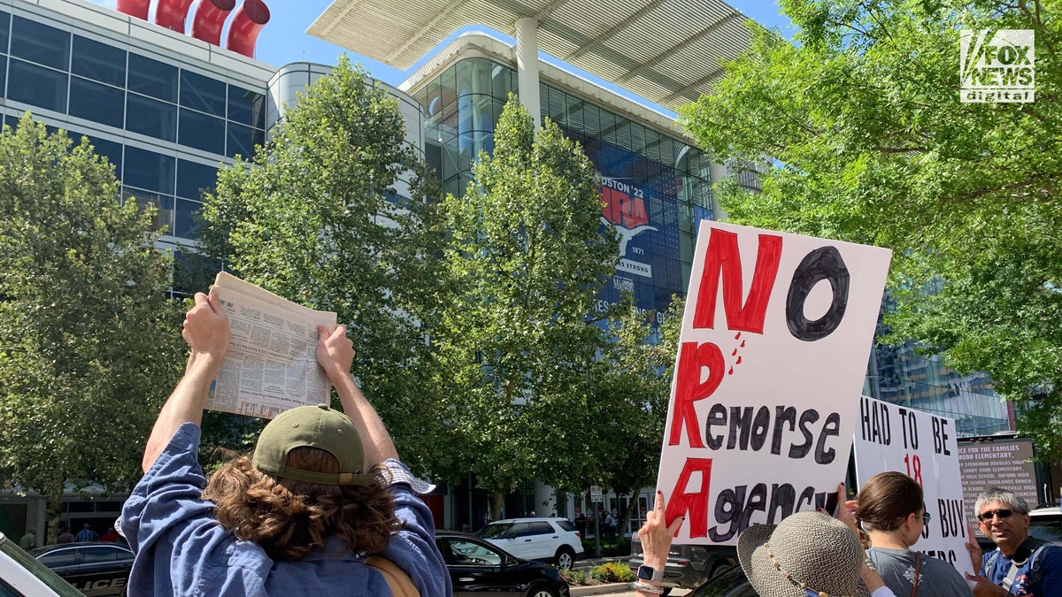 People holding anti-gun signs protesting the NRA convention