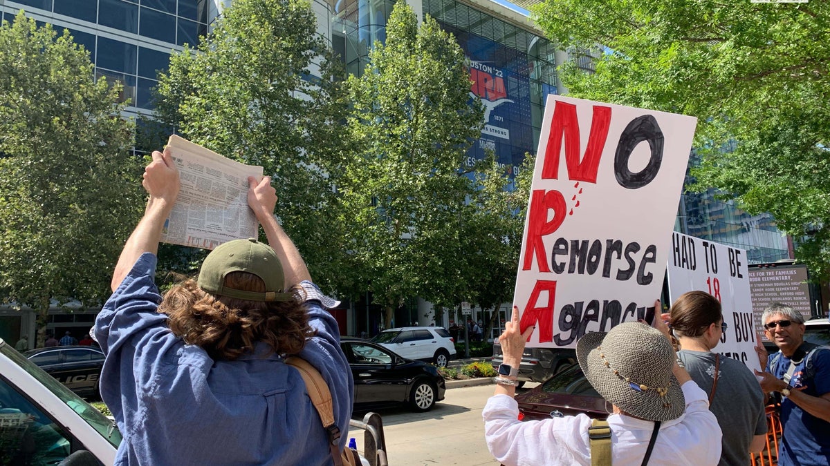 People holding anti-gun signs protesting the NRA convention