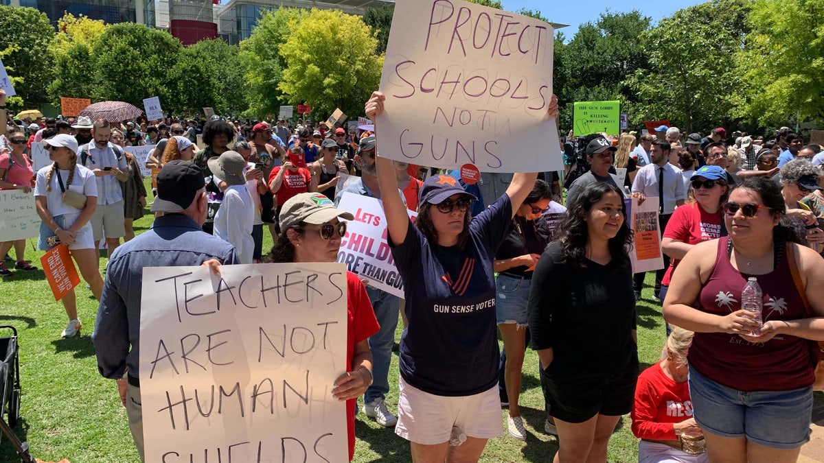 NRA protesters stand outside holding signs