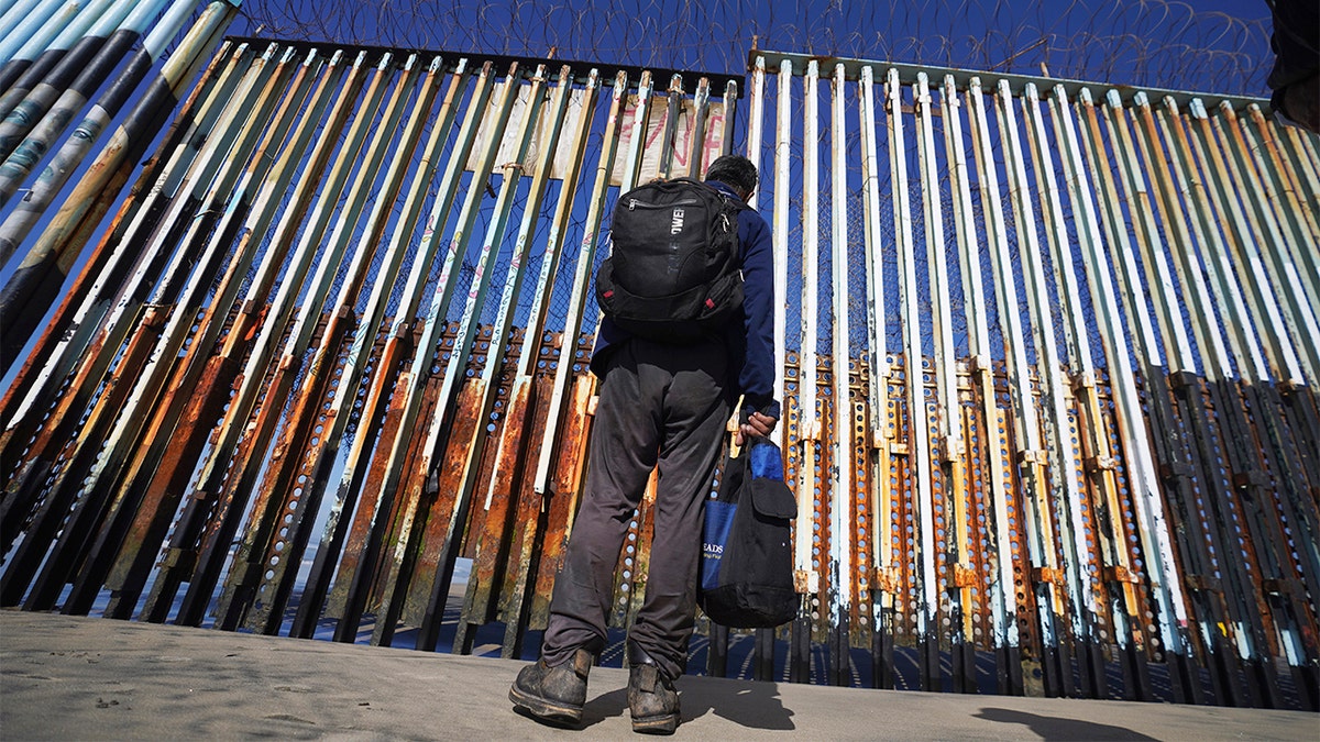 A migrant waits on the Mexican side of the border