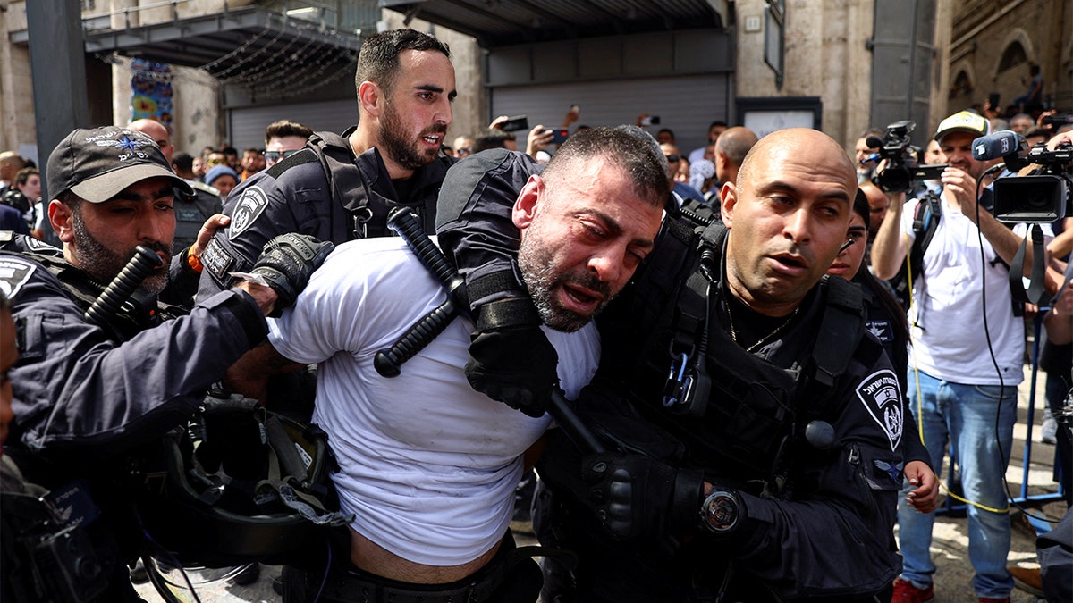 Members of the Israeli security forces detain a man during the funeral of Al Jazeera reporter Shireen Abu Akleh, who was killed during an Israeli raid in Jenin in the occupied West Bank, in Jerusalem, May 13, 2022. REUTERS/Ronen Zvulun