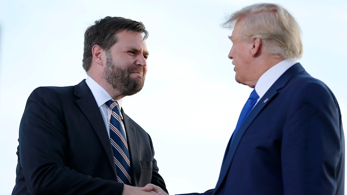 Senate candidate JD Vance, left, greets former President Donald Trump at a rally