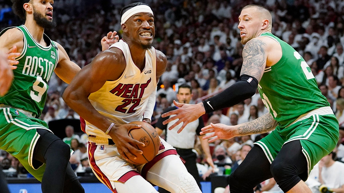 Miami Heat forward Jimmy Butler (22) drives to the basket between Boston Celtics guard Derrick White (9) and center Daniel Theis (27) during the second half of Game 1 of an NBA basketball Eastern Conference finals playoff series, Tuesday, May 17, 2022, in Miami.