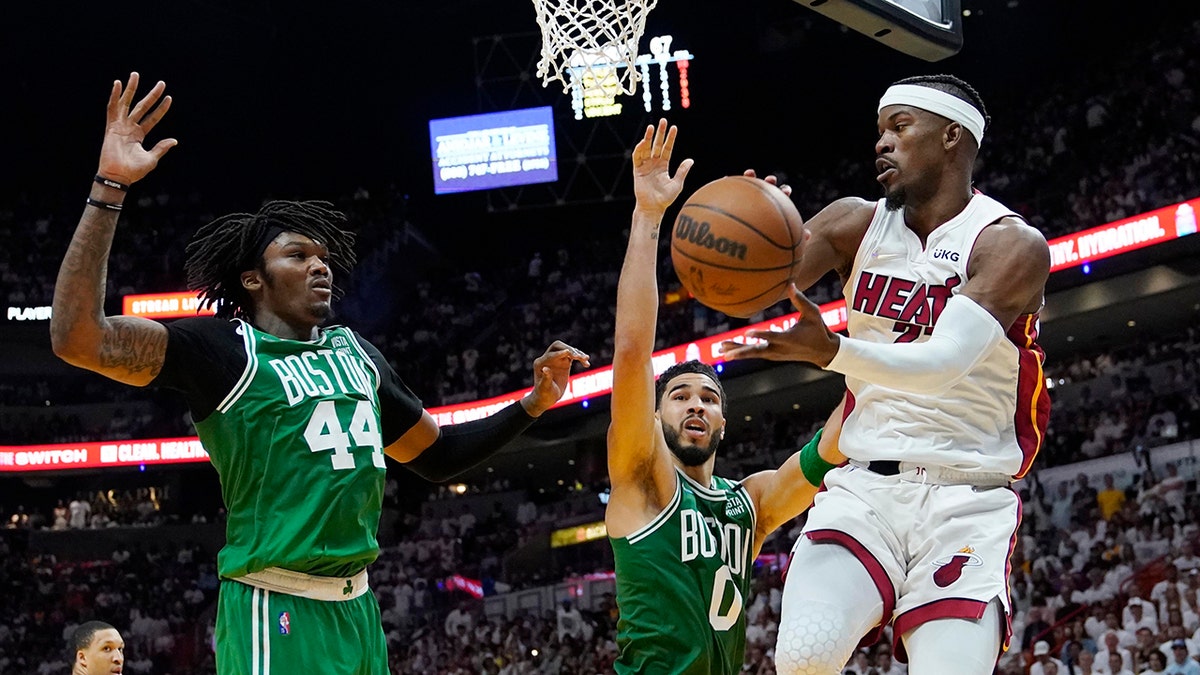 Boston Celtics center Robert Williams III (44) and forward Jayson Tatum (0) attempt to block a pass by Miami Heat forward Jimmy Butler (22) during the second half of Game 1 of an NBA basketball Eastern Conference finals playoff series, Tuesday, May 17, 2022, in Miami.