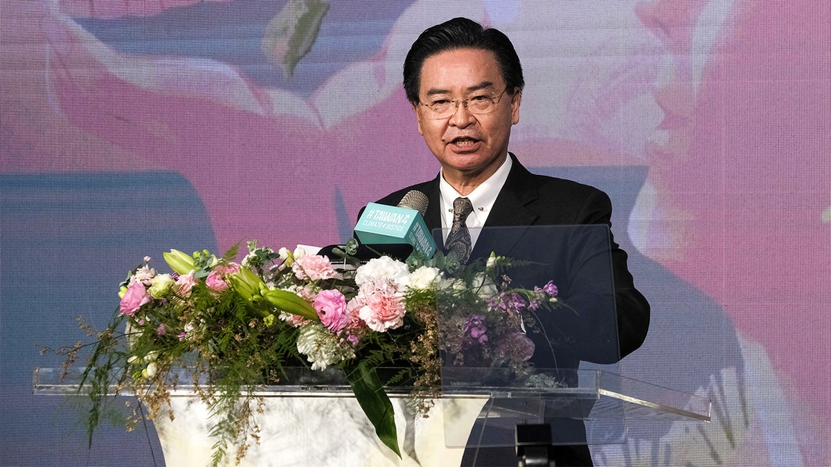 Tawain's Joseph Wu in a black suit gives a speech at flower decorate podium