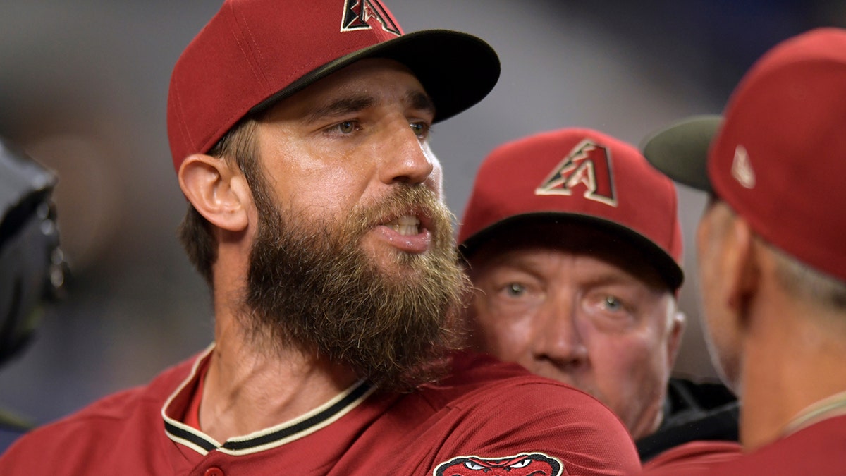 Arizona Diamondbacks' pitcher Madison Bumgarner, center, is restrained by bench coach Jeff Banister, rear, while arguing with umpires after the first inning of a baseball game against the against the Miami Marlins, Wednesday, May 4, 2022, in Miami.