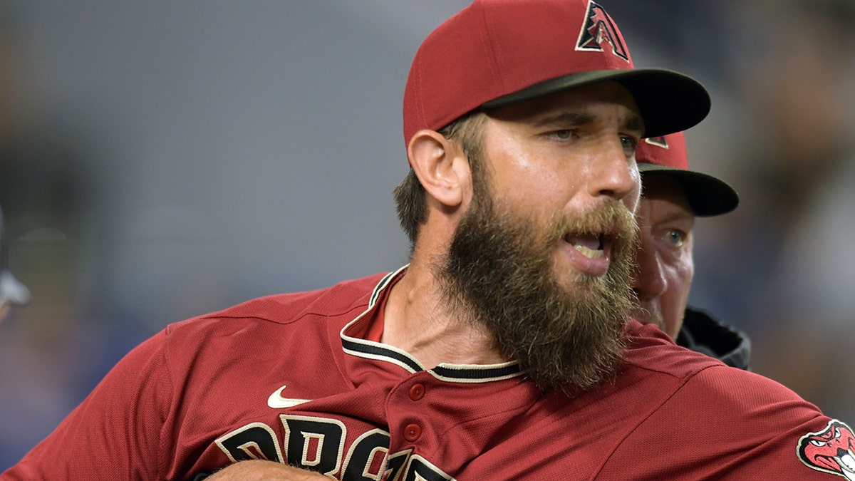 Arizona Diamondbacks' pitcher Madison Bumgarner, left, is restrained by bench coach Jeff Banister while arguing with umpires after the first inning of a baseball game against the against the Miami Marlins, Wednesday, May 4, 2022, in Miami.