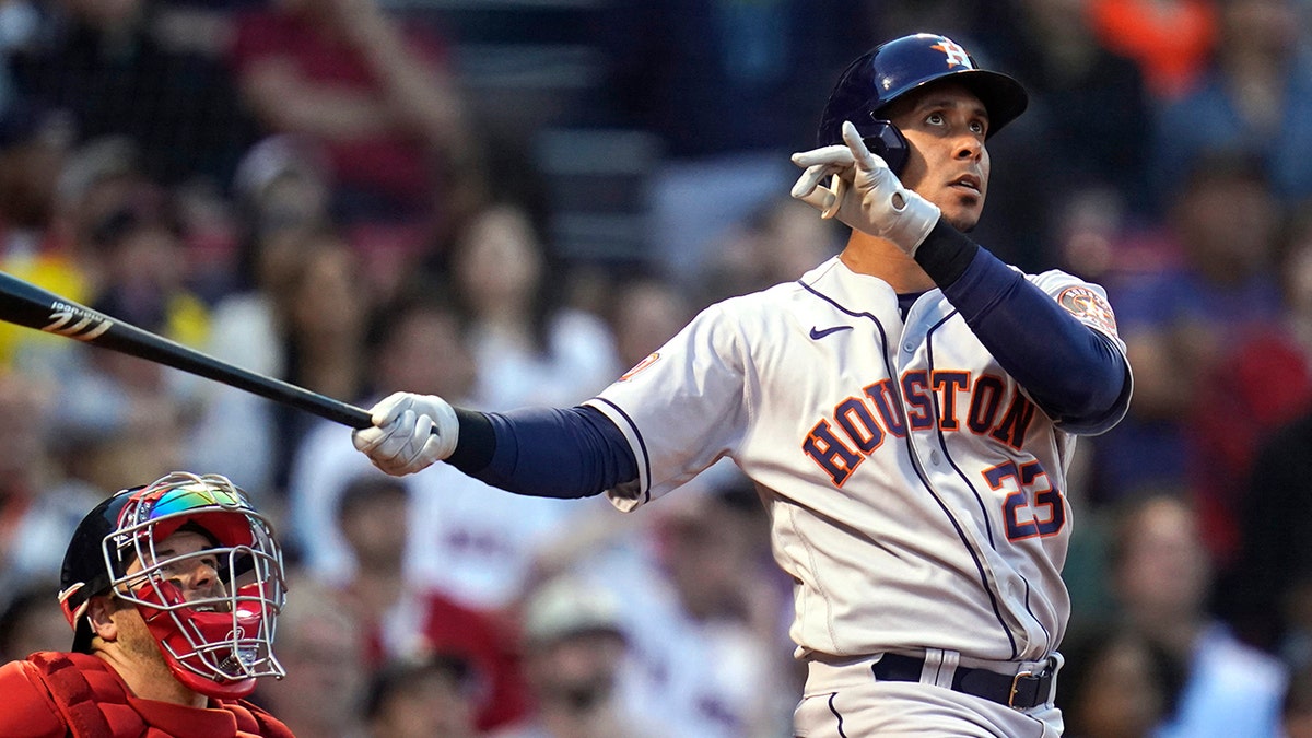 Houston Astros' Michael Brantley watches his two-run home run next to Boston Red Sox catcher Kevin Plawecki  during the second inning of a baseball game at Fenway Park, Tuesday, May 17, 2022, in Boston.