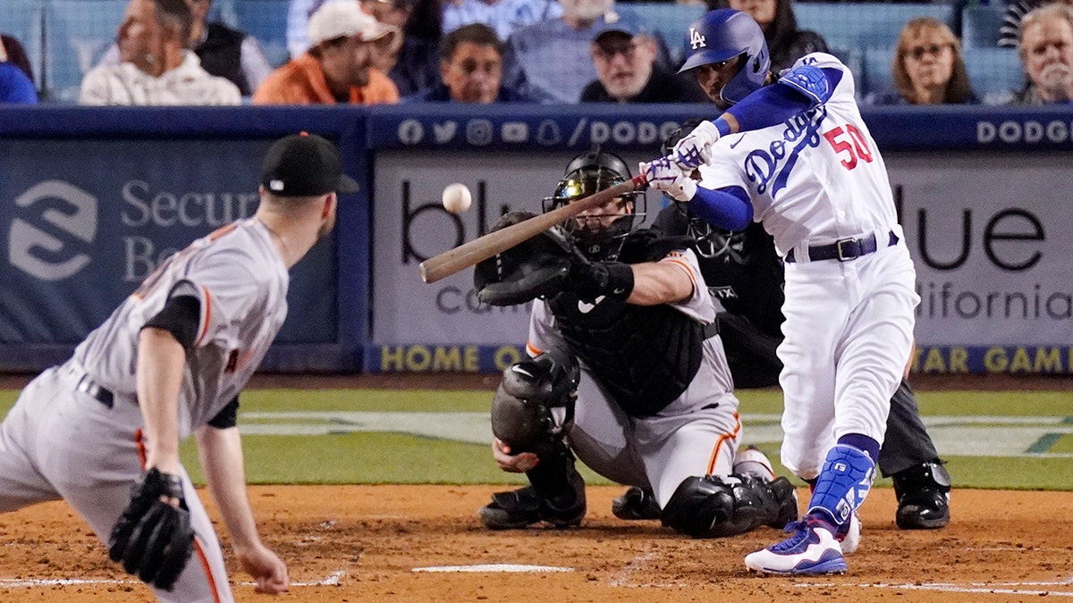 Los Angeles Dodgers right fielder Mookie Betts, right, hits a solo home run as San Francisco Giants starting pitcher Alex Wood, left, and catcher Joey Bart watch during the sixth inning of a baseball game Wednesday, May 4, 2022, in Los Angeles.
