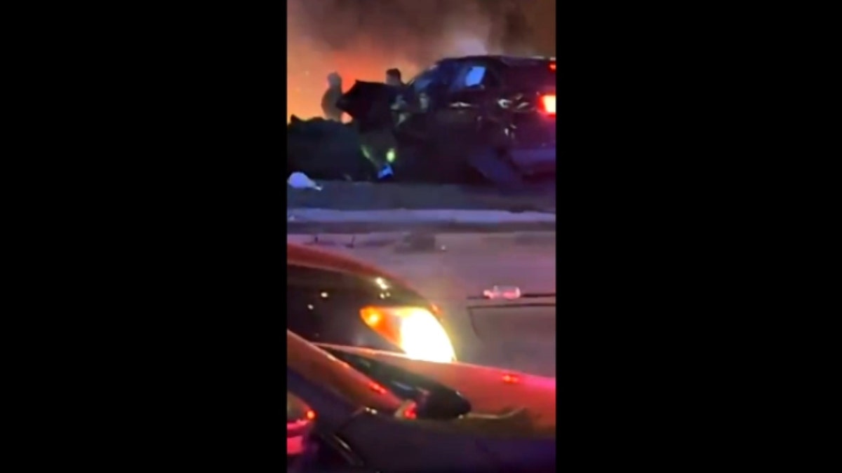 A damaged, black vehicle emits what appears to be smoke following a car crash in Lincoln, Nebraska, on Sunday.