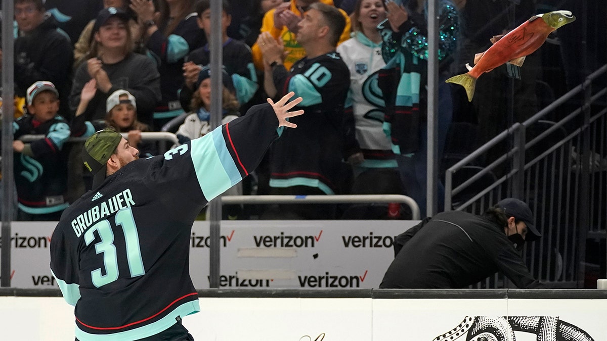 Seattle Kraken goaltender Philipp Grubauer tosses a stuffed salmon to fans after the team's NHL hockey game against the San Jose Sharks, Friday, April 29, 2022, in Seattle. The Kraken won 3-0.