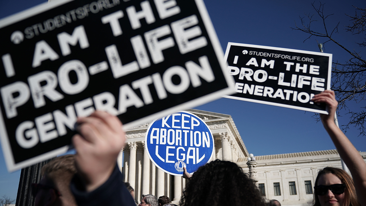 Pro-life signs and abortion signs being held in front of SCOTUS