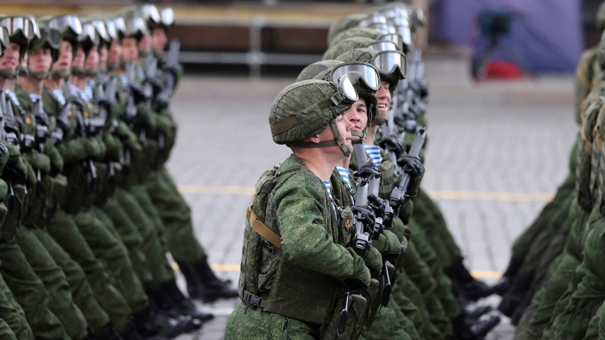 Russian service members march in uniform in military parade