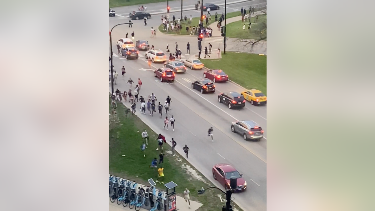 A large group of young people run through the streets of Chicago on Wednesday, May 11, 2022.