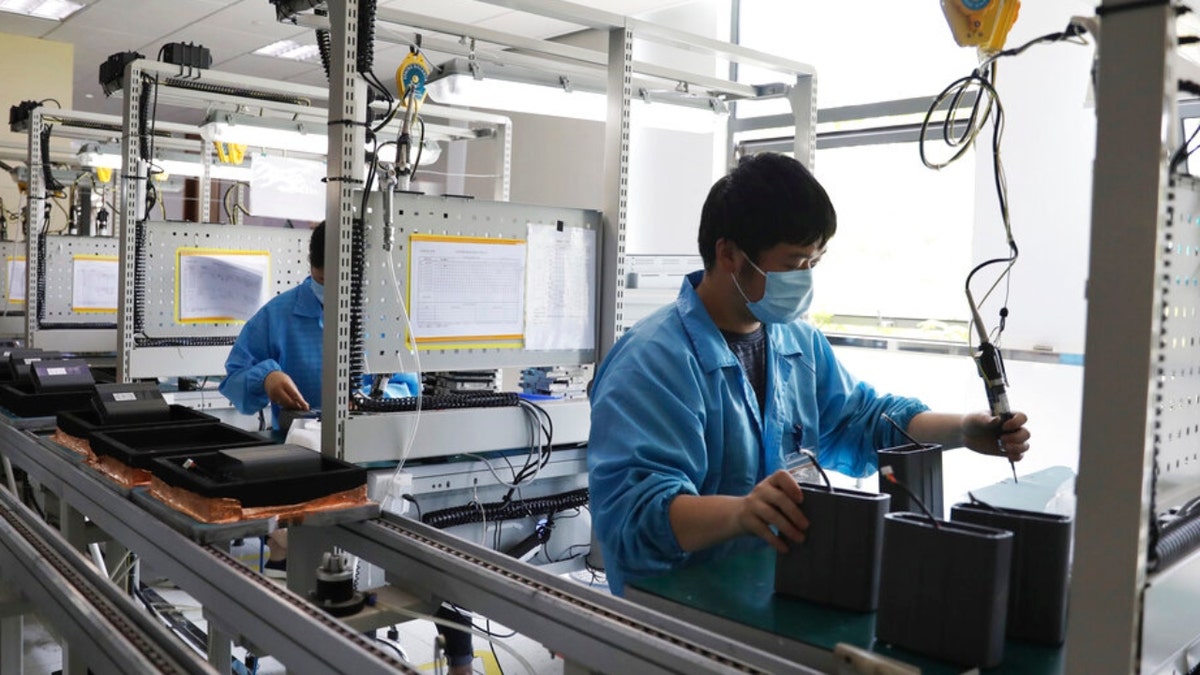 Factory employees operate while wearing masks