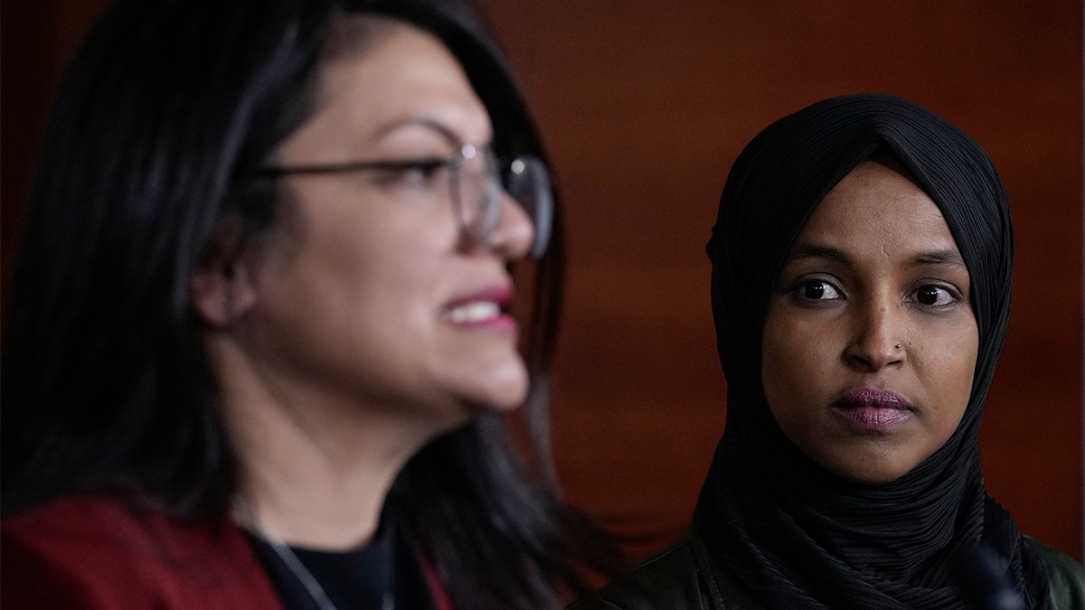 A deputada Ilhan Omar, democrata de Minnesota, ouve enquanto a deputada Rashida Tlaib, democrata de Minnesota, fala durante uma entrevista coletiva sobre a islamofobia no Capitólio em 30 de novembro de 2021 em Washington.  (Foto de Drew Angerer/Getty Images)