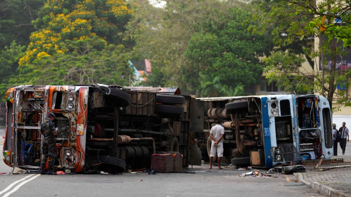 Sri Lankan government soldiers stand guard near burnt buses