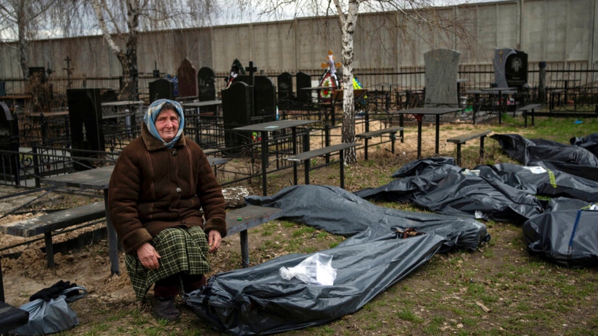 A woman sits next to the bodies of Bucha soldiers