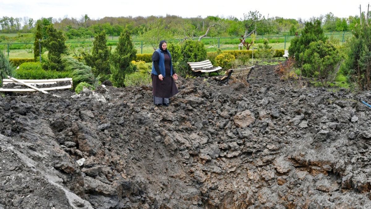 Orthodox Sister Evdokia gestures in front of the crater of an explosion near Slovyansk
