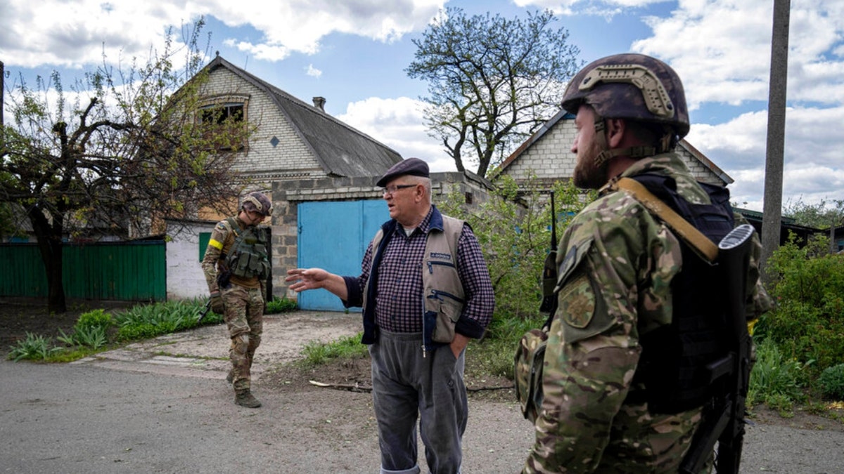 A Ukrainian serviceman talks with a local resident in Maksymilyanivka